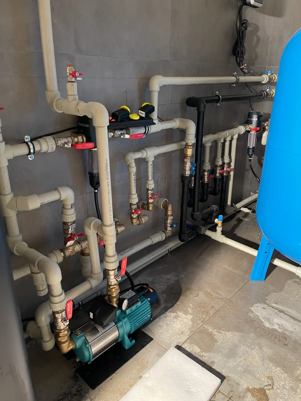Instalacje hydrauliczne: pompa, zawory, filtry i zbiornik ciśnieniowy w pomieszczeniu technicznym