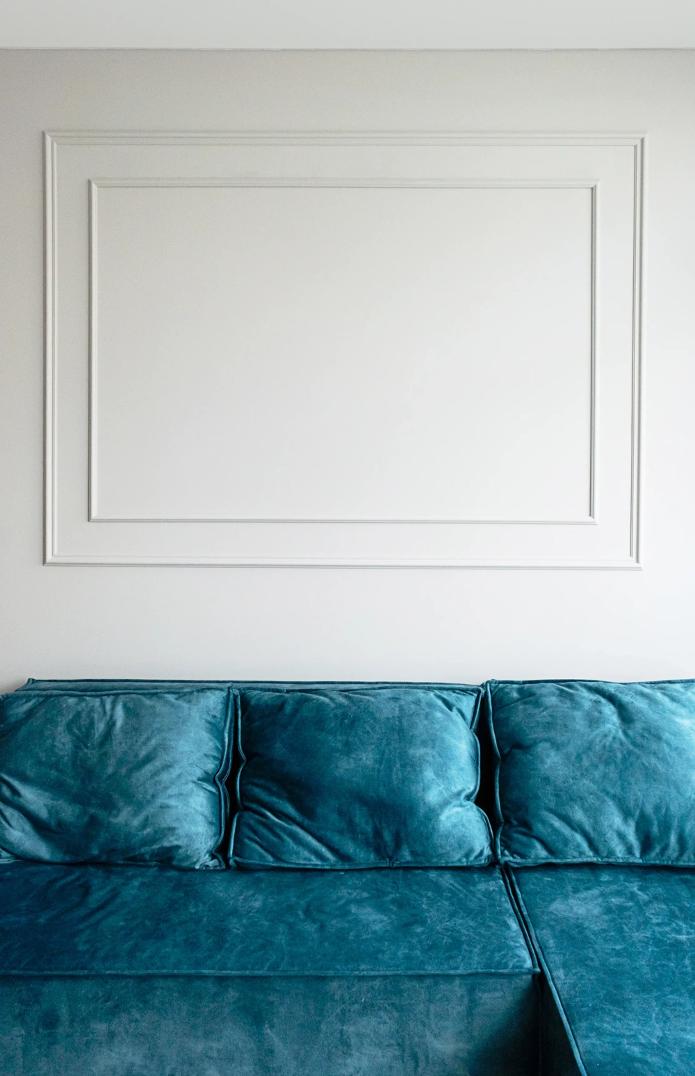 Turkusowa sofa na tle białej ściany ze sztukaterią Sztukateria