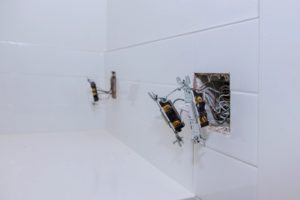 Otwory w białej ścianie z przewodami przygotowane pod instalacje elektryczne